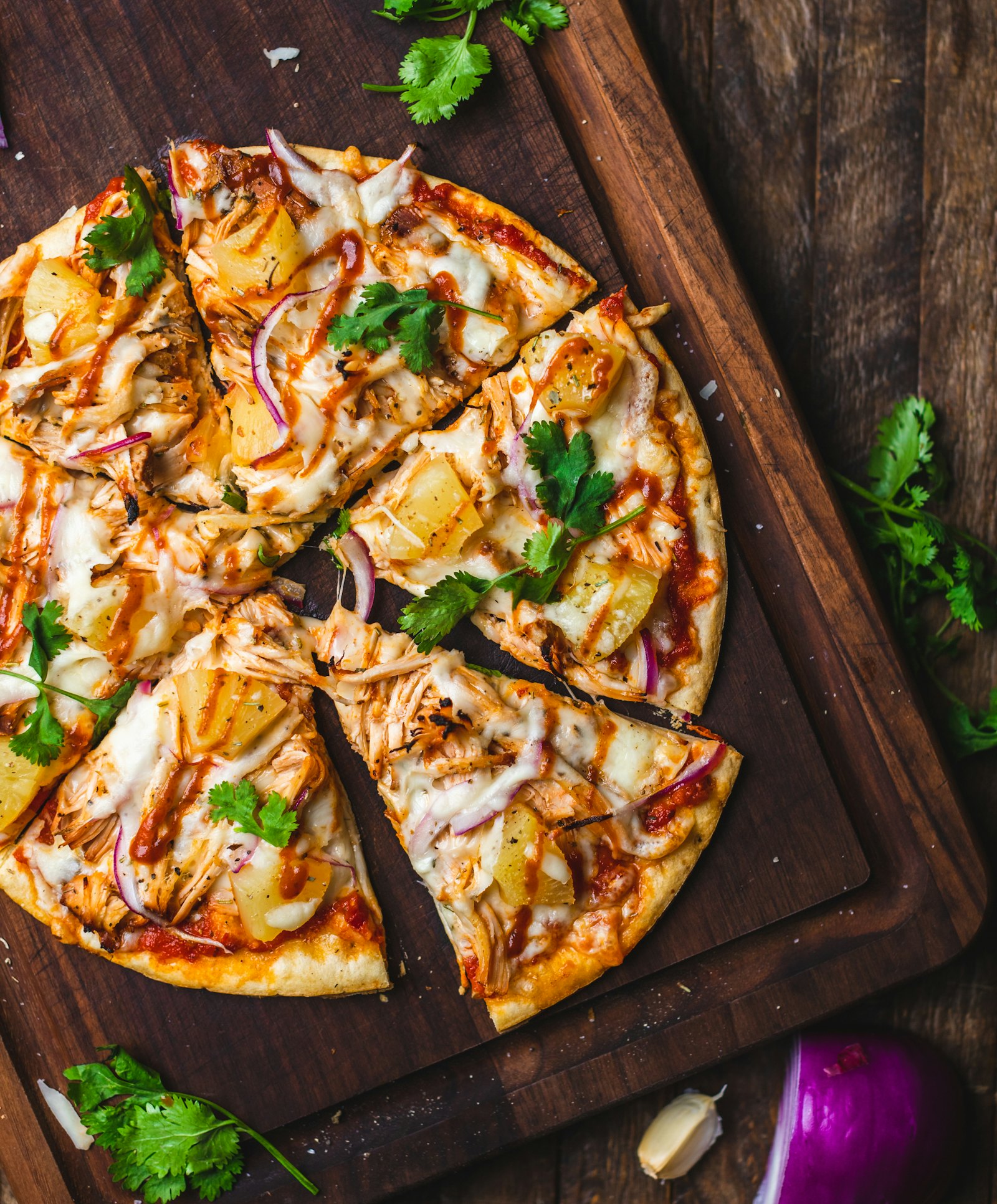 Pizza com frango e cebola roxa sobre tábua de madeira